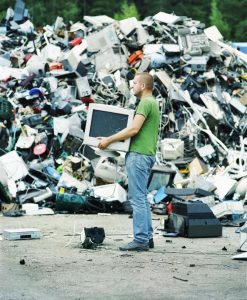 Man holding a computer monitor at a recycling center